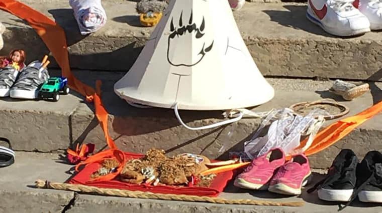 Many pairs of shoes, a miniature teepee, stuffed toys and other items on steps.
