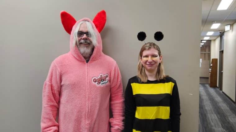 Two people standing in hall, one in a bunny costume and one in a bee costume.